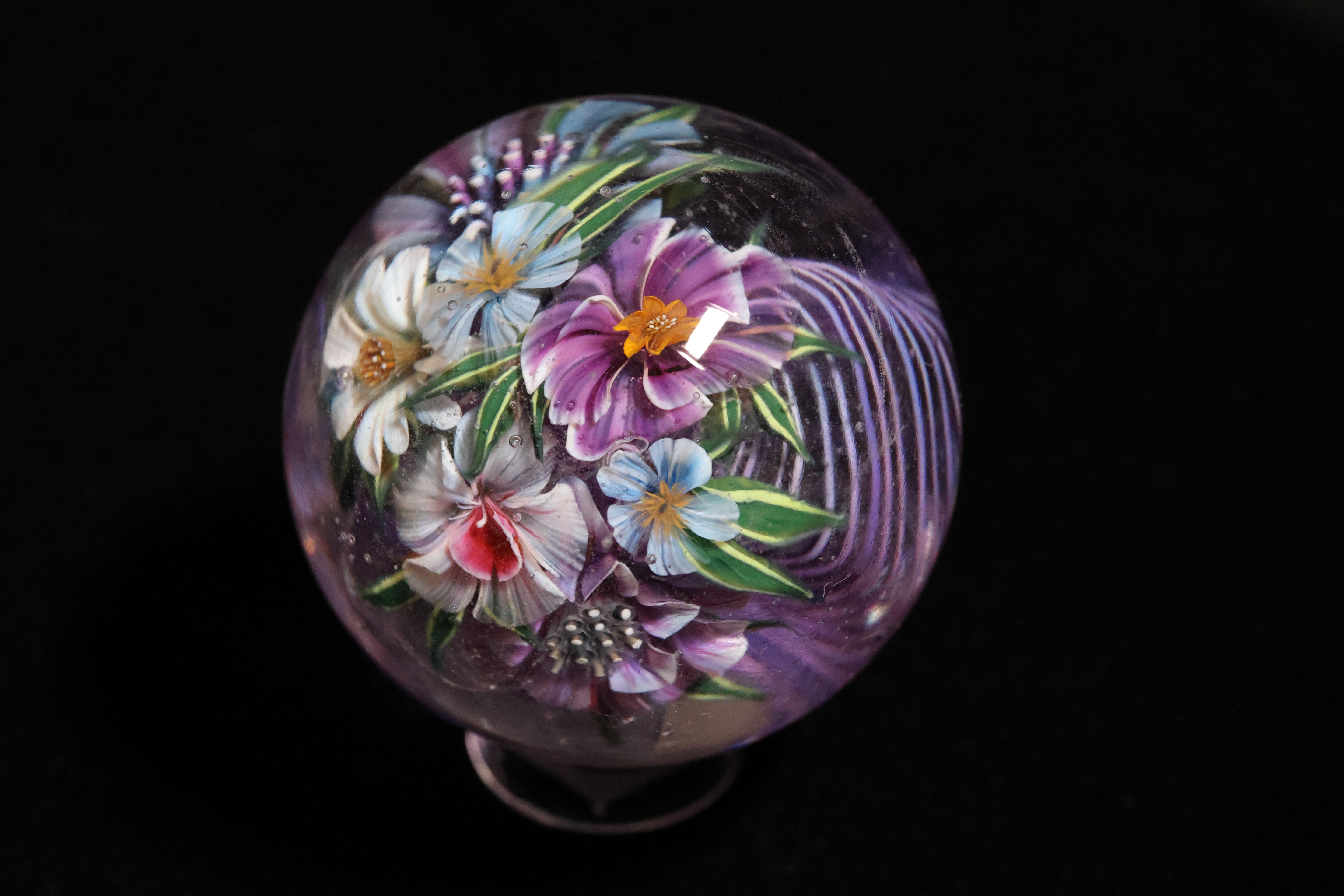 Decorative glass marble with floral design on a black background